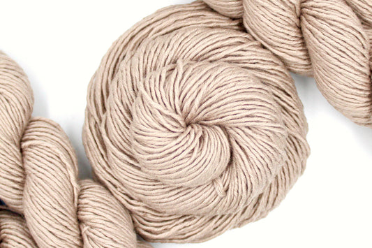 A skein of Tan, 40% Wool, 30% Nylon, 30% Modal, Worsted Weight Yarn recycled by hand from unwanted sweaters swirled attractively in the center of the frame. 