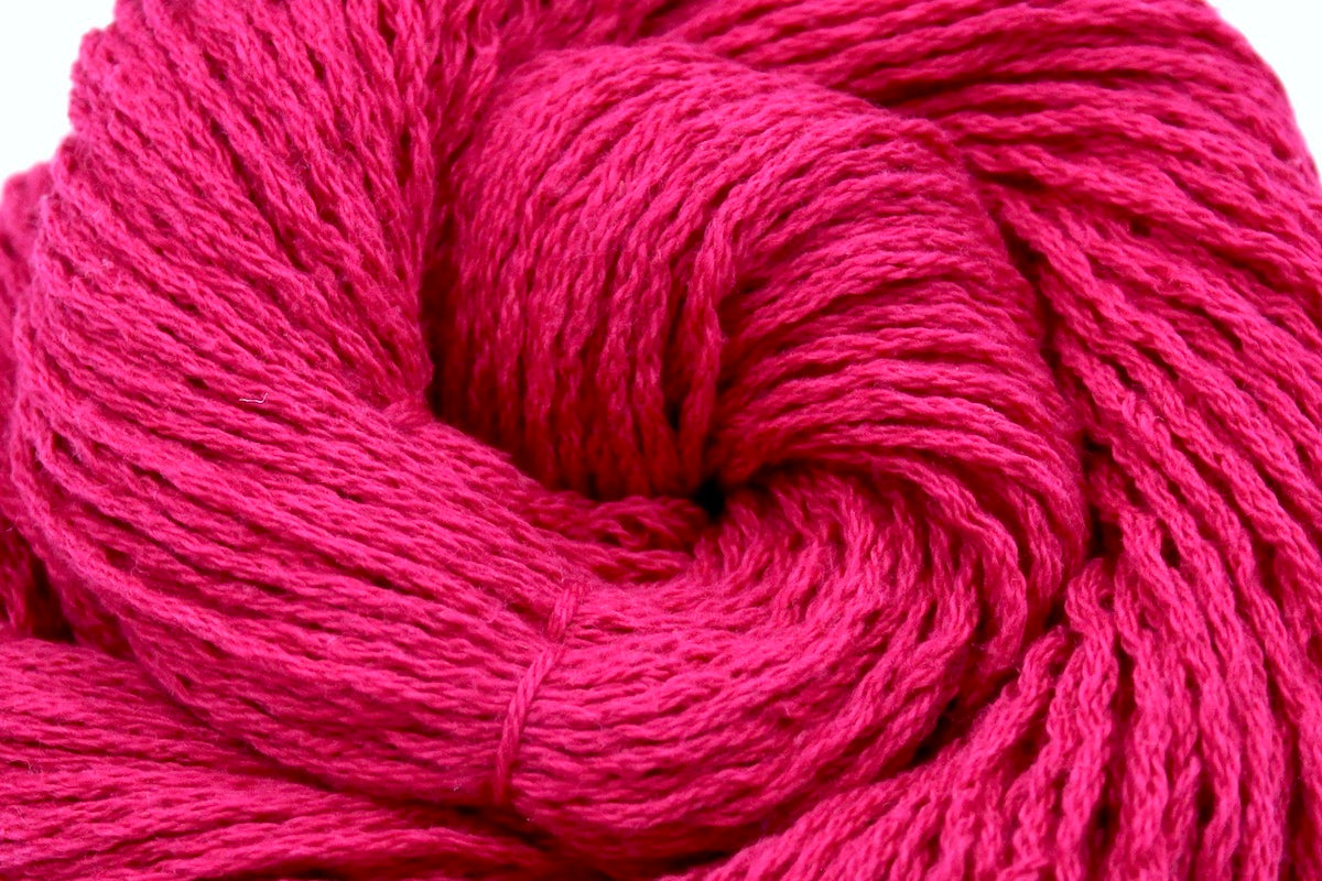 A close up shot of a skein of Hot Pink Fuchsia, Cotton/ Nylon/ Wool/ Polyester, Worsted weight Yarn recycled by hand from unwanted sweaters beautifully coiled in the center of the frame. 
