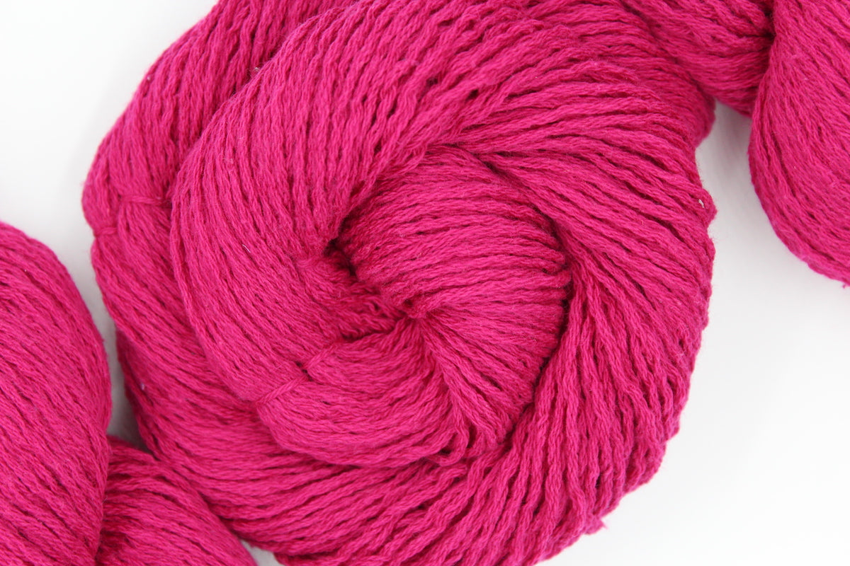 A skein of Hot Pink Fuchsia, Cotton/ Nylon/ Wool/ Polyester, Worsted weight Yarn recycled by hand from unwanted sweaters swirled attractively in the center of the frame. 