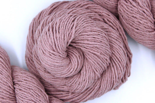 A skein of Dusky Pink, Cotton/ Acrylic, Dk weight Yarn recycled by hand from unwanted sweaters swirled attractively in the center of the frame. 