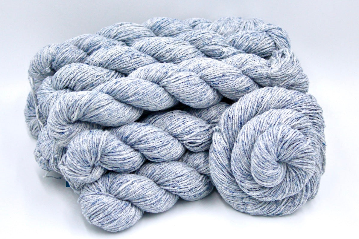 Several skeins of Pale Blue Speckled, Cotton/ Acrylic, Dk weight recycled by hand from unwanted sweaters stacked on top of each other attractively. 