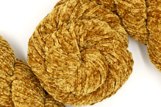 A skein of Yellow Gold, Chenille Polyester, Worsted weight Yarn recycled by hand from unwanted sweaters swirled attractively in the center of the frame. 