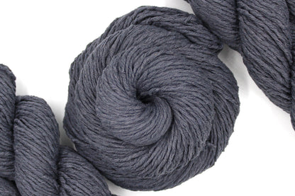 A skein of Vegan, Dark Grey, 60% Cotton, 40% Acrylic, Worsted Weight Yarn recycled by hand from unwanted sweaters swirled attractively in the center of the frame. 