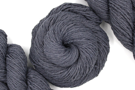 A skein of Vegan, Dark Grey, 60% Cotton, 40% Acrylic, Worsted Weight Yarn recycled by hand from unwanted sweaters swirled attractively in the center of the frame. 