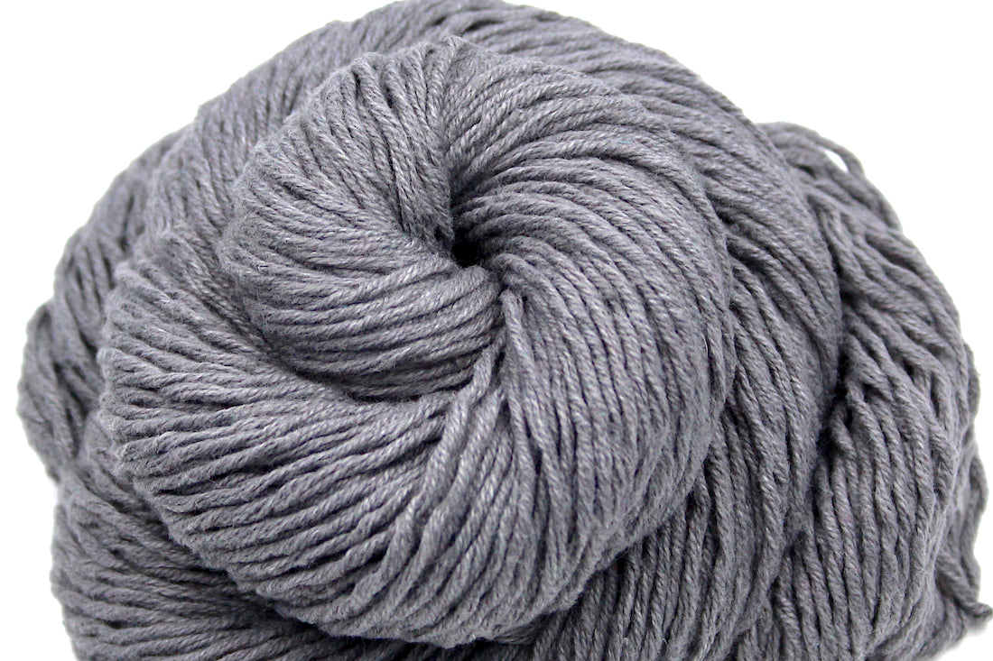 A close up shot of a skein of Vegan, medium Grey, 60% Cotton, 40% Acrylic, Dk Weight Yarn recycled by hand from unwanted sweaters beautifully coiled in the center of the frame. 