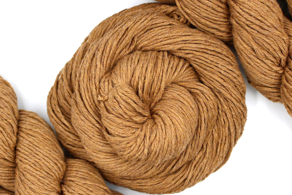 A skein of Vegan, Orangey Brown, 100% Cotton, Worsted Weight Yarn recycled by hand from unwanted sweaters swirled attractively in the center of the frame. 