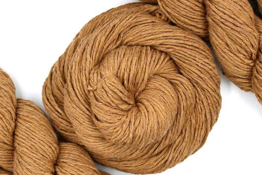A skein of Vegan, Orangey Brown, 100% Cotton, Worsted Weight Yarn recycled by hand from unwanted sweaters swirled attractively in the center of the frame. 
