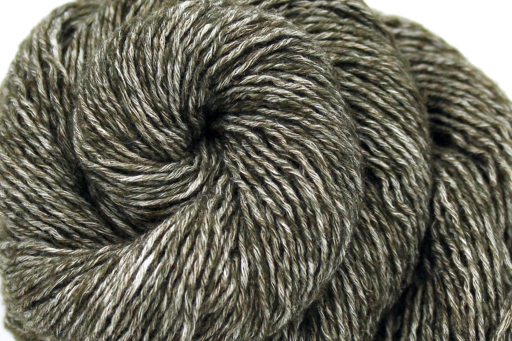A close up shot of a skein of Heathered Olive Green, Cotton/Acrylic, Sport weight Yarn recycled by hand from unwanted sweaters beautifully coiled in the center of the frame. 