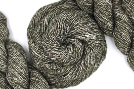 A skein of Heathered Olive Green, Cotton/Acrylic, Sport weight Yarn recycled by hand from unwanted sweaters swirled attractively in the center of the frame. 