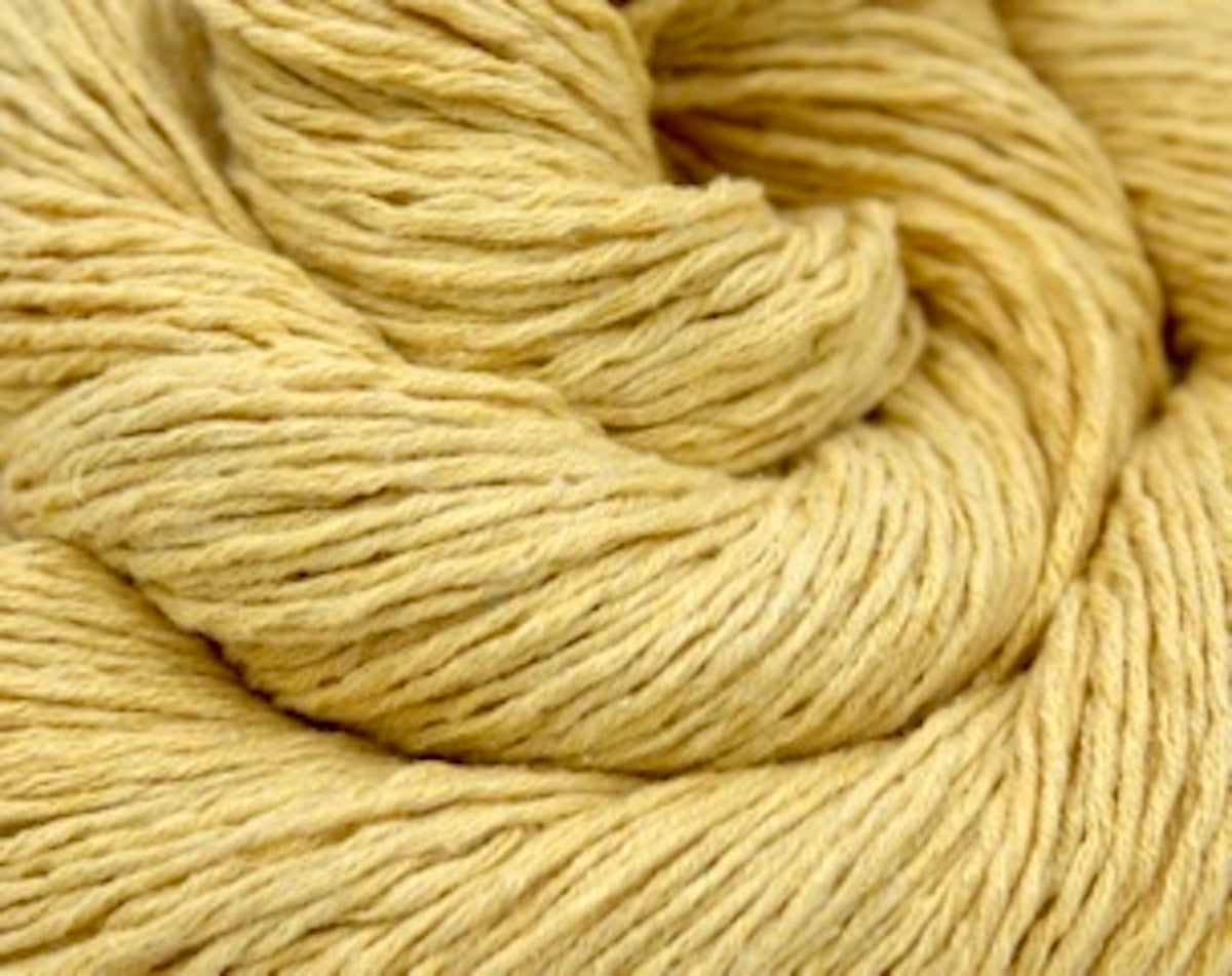 A close up shot of a skein of Golden Yellow, 100% Cotton, Sport weight Yarn recycled by hand from unwanted sweaters beautifully coiled in the center of the frame. 