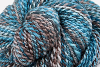 A close up view of a one of a kind, Worsted Weight, hand dyed variegated skein of multicolored Blue, Teal, Taupe, and Chocolate Brown self-striping wool Yarn. 