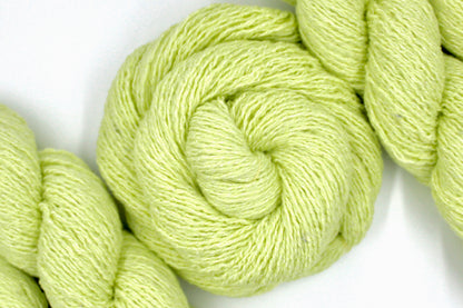A skein of Vegan, Neon Greenish Yellow, Cotton, Acrylic, Polyester, Sport Weight Yarn recycled by hand from unwanted sweaters swirled attractively in the center of the frame. 