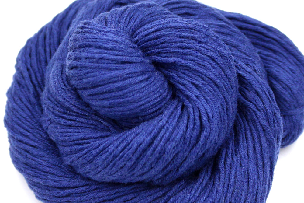 A close up shot of a skein of Vegan, Purplish Blue, Cotton, Nylon, Rayon, Dk Weight Yarn recycled by hand from unwanted sweaters beautifully coiled in the center of the frame. 