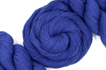 A skein of Vegan, Purplish Blue, Cotton, Nylon, Rayon, Dk Weight Yarn recycled by hand from unwanted sweaters swirled attractively in the center of the frame. 
