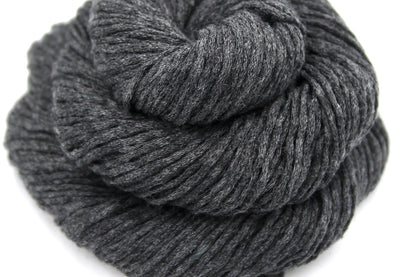 A close up shot of a skein of Vegan, Dark Grey, Acrylic/ Cotton, Dk weight Yarn recycled by hand from unwanted sweaters beautifully coiled in the center of the frame. 