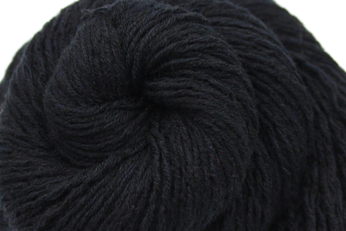 A close up shot of a skein of Vegan, Black, Cotton/ Acrylic, Sport weight Yarn recycled by hand from unwanted sweaters beautifully coiled in the center of the frame. 
