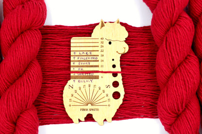 A skein of Vegan, Red, 100% Cotton, Worsted Weight Yarn recycled by hand from unwanted sweaters draped over the center of the frame with one strand on top of a Llama shaped Yarn weight tool, to better illustrate the thickness of the yarn. 