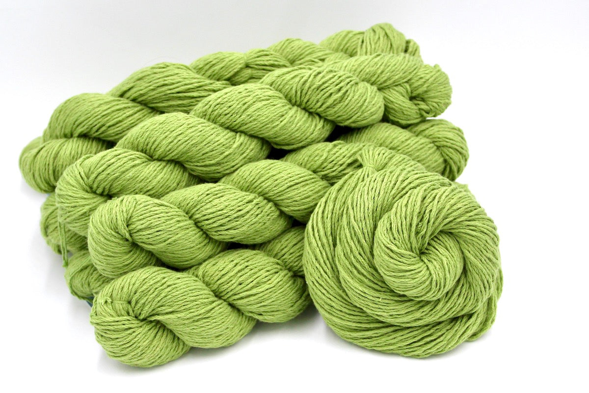 Several skeins of Vegan, Lime Green/ Chartreuse, Cotton/ Acrylic, Dk weight recycled by hand from unwanted sweaters stacked on top of each other attractively. 