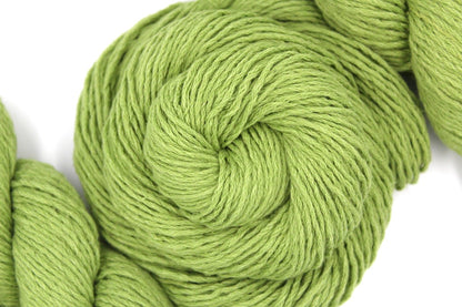 A skein of Vegan, Lime Green/ Chartreuse, Cotton/ Acrylic, Dk weight Yarn recycled by hand from unwanted sweaters swirled attractively in the center of the frame. 