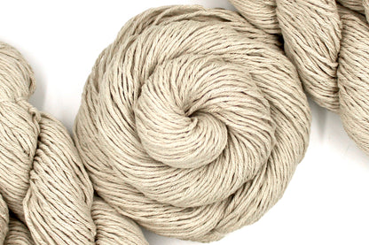 A skein of Vegan, light beige, 100% Cotton, Worsted Weight Yarn recycled by hand from unwanted sweaters swirled attractively in the center of the frame. 