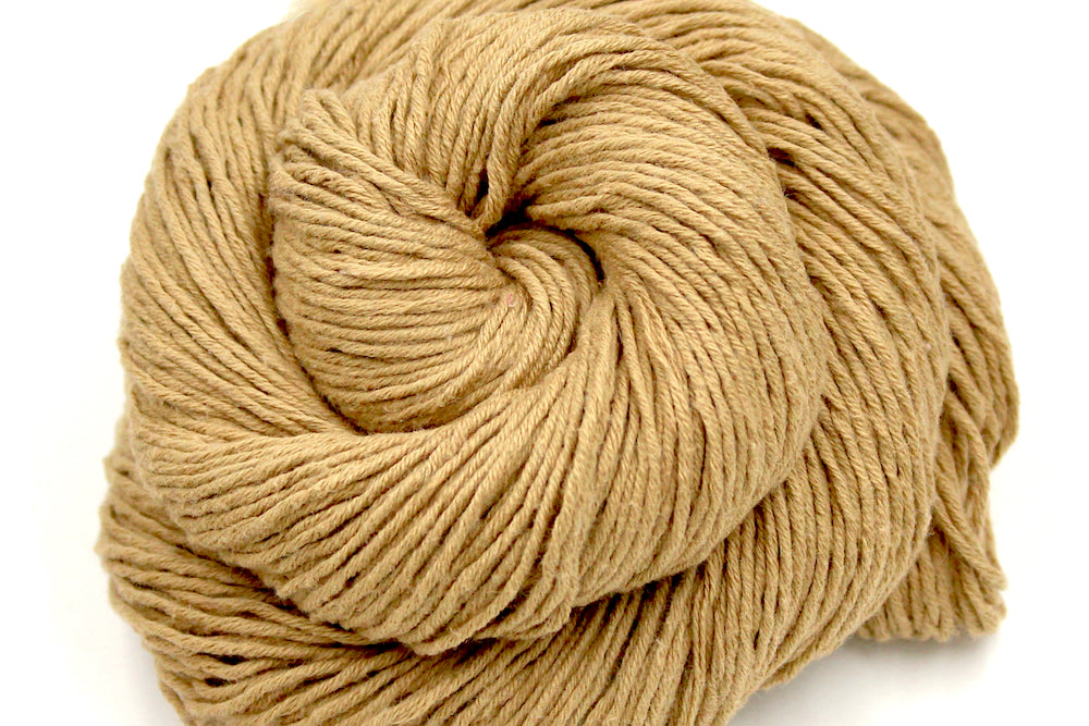 A close up shot of a skein of Vegan, golden tan, 100% Cotton, Sport Weight Yarn recycled by hand from unwanted sweaters beautifully coiled in the center of the frame. 