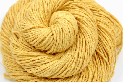 A close up shot of a skein of Vegan, Mustard Yellow, Cotten blend, DK Weight Yarn recycled by hand from unwanted sweaters beautifully coiled in the center of the frame. 