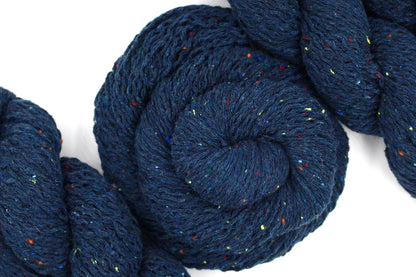 A skein of Dark Blue and Rainbow Tweed, Wool and Acrylic, Sport Weight Yarn recycled by hand from unwanted sweaters swirled attractively in the center of the frame. 