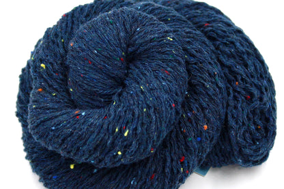A close up shot of a skein of Dark Blue and Rainbow Tweed, Wool and Acrylic, Sport Weight Yarn recycled by hand from unwanted sweaters beautifully coiled in the center of the frame. 