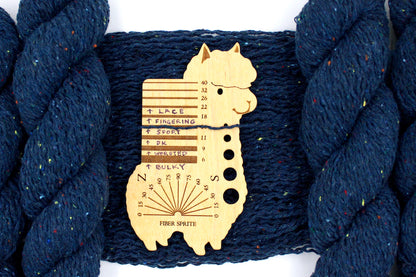 A skein of Dark Blue and Rainbow Tweed, Wool and Acrylic, Sport Weight Yarn recycled by hand from unwanted sweaters draped over the center of the frame with one strand on top of a Llama shaped Yarn weight tool, to better illustrate the thickness of the yarn. 