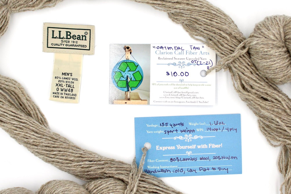 A skein of Tan/ Ecru/ Beige/ Taupe, Lamb's Wool/ Nylon, Sport Weight yarn encircling the sweater labels it was recycled from, as well as the hand written yarn tags detailing the specs of this upcycled yarn to help you make your next project! 