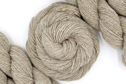 A skein of Tan/ Ecru/ Beige/ Taupe, Lamb's Wool/ Nylon, Sport weight Yarn recycled by hand from unwanted sweaters swirled attractively in the center of the frame. 
