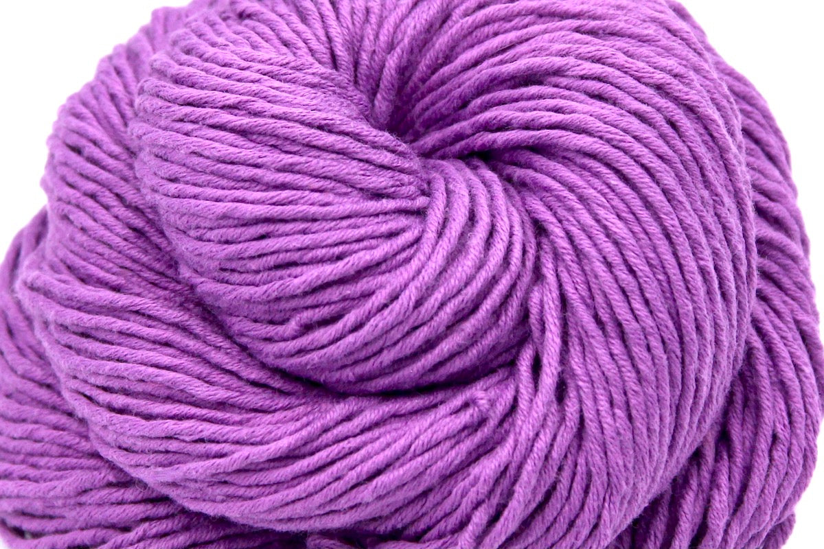 A close up shot of a skein of Vegan, Purplish Pink Orchid, 100% Cotton, Worsted weight Yarn recycled by hand from unwanted sweaters beautifully coiled in the center of the frame. 