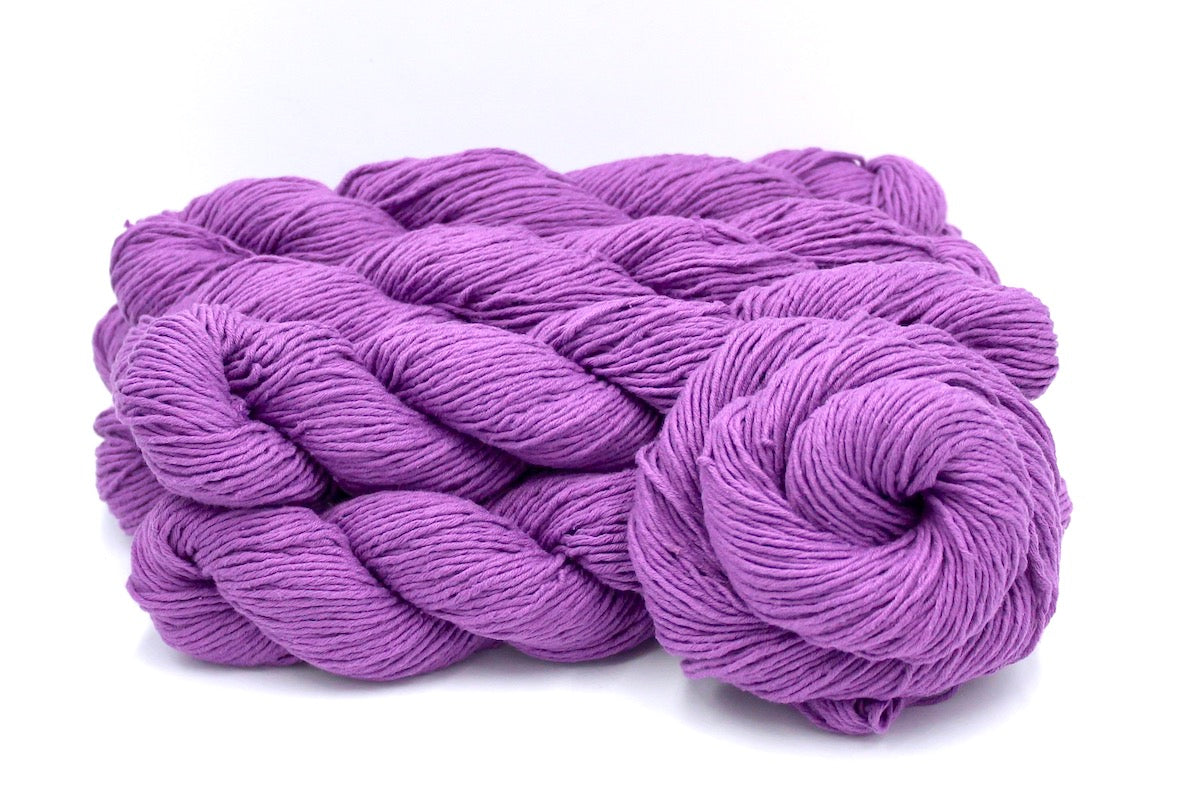 Several skeins of Vegan, Purplish Pink Orchid, 100% Cotton, Worsted weight recycled by hand from unwanted sweaters stacked on top of each other attractively. 