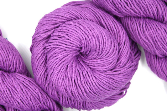 A skein of Vegan, Purplish Pink Orchid, 100% Cotton, Worsted weight Yarn recycled by hand from unwanted sweaters swirled attractively in the center of the frame. 