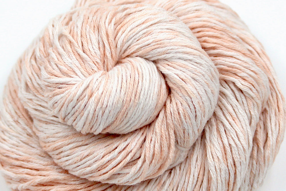 A skein of Vegan, Variegated Pink and Cream, 100% Cotton, Sport Weight Yarn recycled by hand from unwanted sweaters swirled attractively in the center of the frame. 