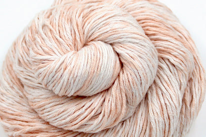 A skein of Vegan, Variegated Pink and Cream, 100% Cotton, Sport Weight Yarn recycled by hand from unwanted sweaters swirled attractively in the center of the frame. 