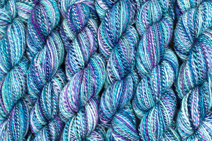 Six one of a kind, Dk Weight, hand dyed variegated skeins of multicolored Blue, Pink, and Purple self-striping Hand spun Yarn, made of 100% Hand Dyed Superwash Merino Wool lined up side by side. 