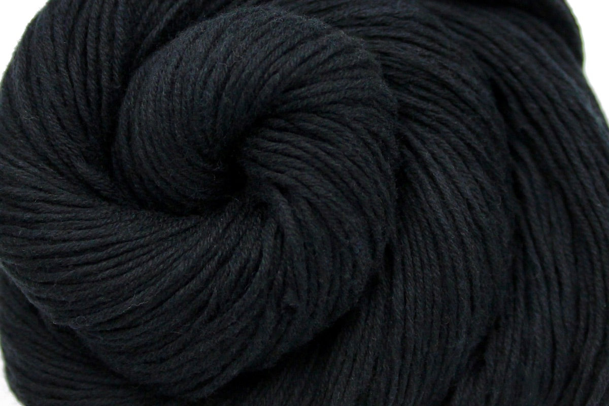 A close up shot of a skein of Vegan, Black, 100% Cotton, Fingering weight Yarn recycled by hand from unwanted sweaters beautifully coiled in the center of the frame. 
