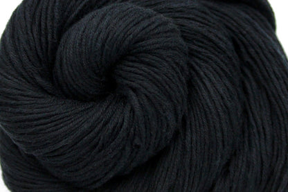 A close up shot of a skein of Vegan, Black, 100% Cotton, Fingering weight Yarn recycled by hand from unwanted sweaters beautifully coiled in the center of the frame. 