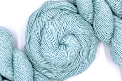 A skein of Vegan, Pastel Baby Blue, Cotton/ Acrylic, Dk weight Yarn recycled by hand from unwanted sweaters swirled attractively in the center of the frame. 