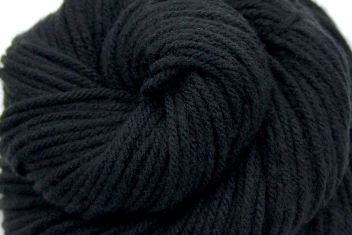 A close up shot of a skein of Vegan, Black, 100% Acrylic, Worsted weight Yarn recycled by hand from unwanted sweaters beautifully coiled in the center of the frame. 