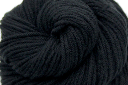 A close up shot of a skein of Vegan, Black, 100% Acrylic, Worsted weight Yarn recycled by hand from unwanted sweaters beautifully coiled in the center of the frame. 