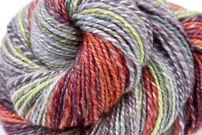 A close up view of a one of a kind, hand dyed gradient skein of multicolored Grey, Lime Green, Olive Green, Maroon, and Bright Peach self-striping wool Yarn. 