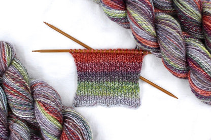 A sample swatch knitted from a one of a kind, hand dyed gradient skein of multicolored Grey, Lime Green, Olive Green, Maroon, and Bright Peach self-striping wool Yarn. 