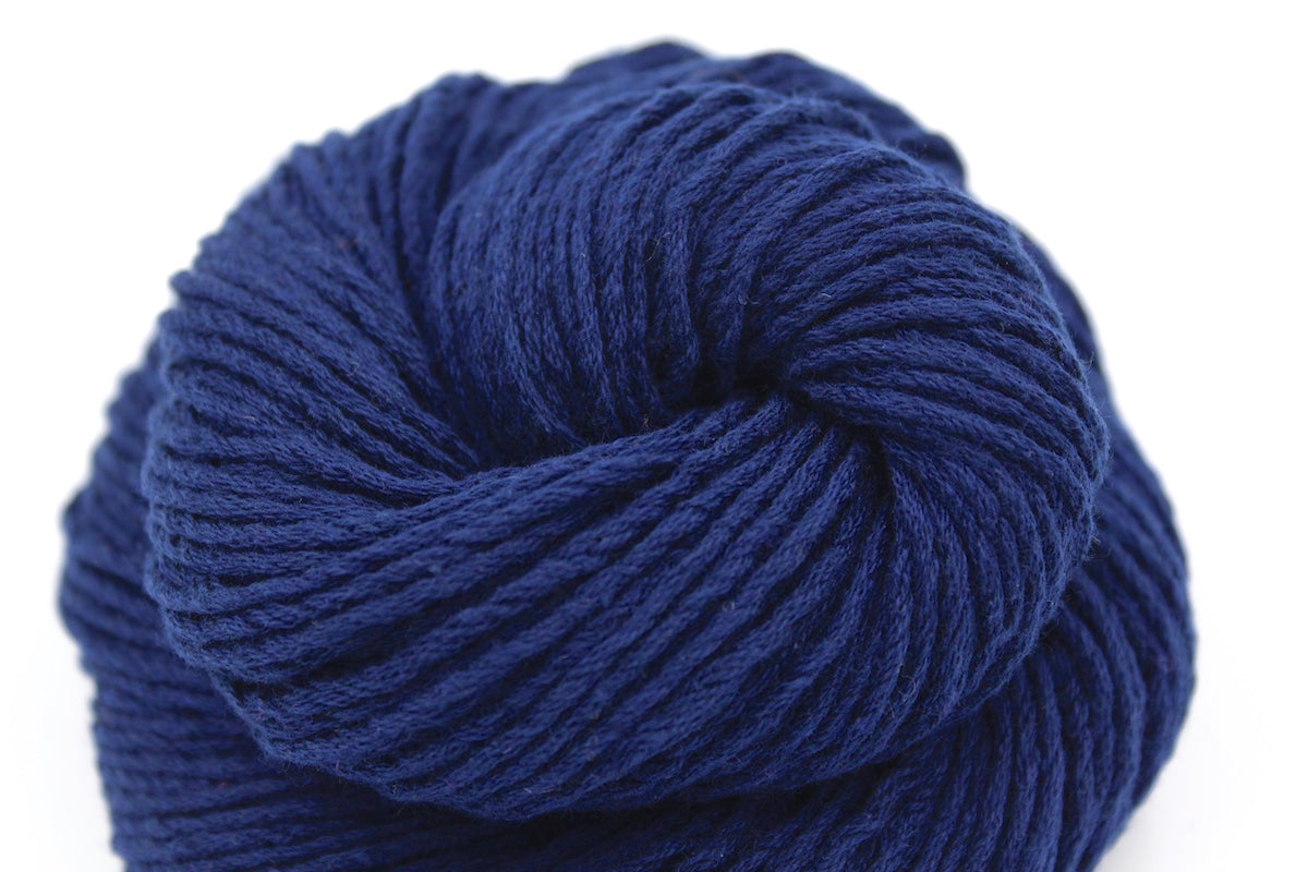 A close up shot of a skein of Vegan, Sailor Navy Blue, Cotton/ Polyester/ Acrylic, Dk weight Yarn recycled by hand from unwanted sweaters beautifully coiled in the center of the frame. 