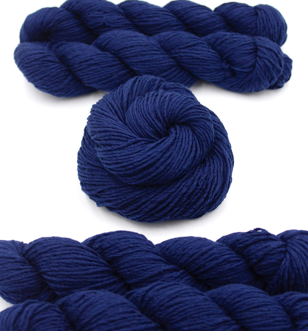 Several skeins of Vegan, Sailor Navy Blue, Cotton/ Polyester/ Acrylic, Dk weight recycled by hand from unwanted sweaters stacked on top of each other attractively. 