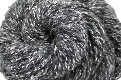 A close up shot of a skein of Heathered Charcoal Grey and White, Wool/ Acrylic/ Cotton/ Polyester, Heavy Worsted weight Yarn recycled by hand from unwanted sweaters beautifully coiled in the center of the frame. 