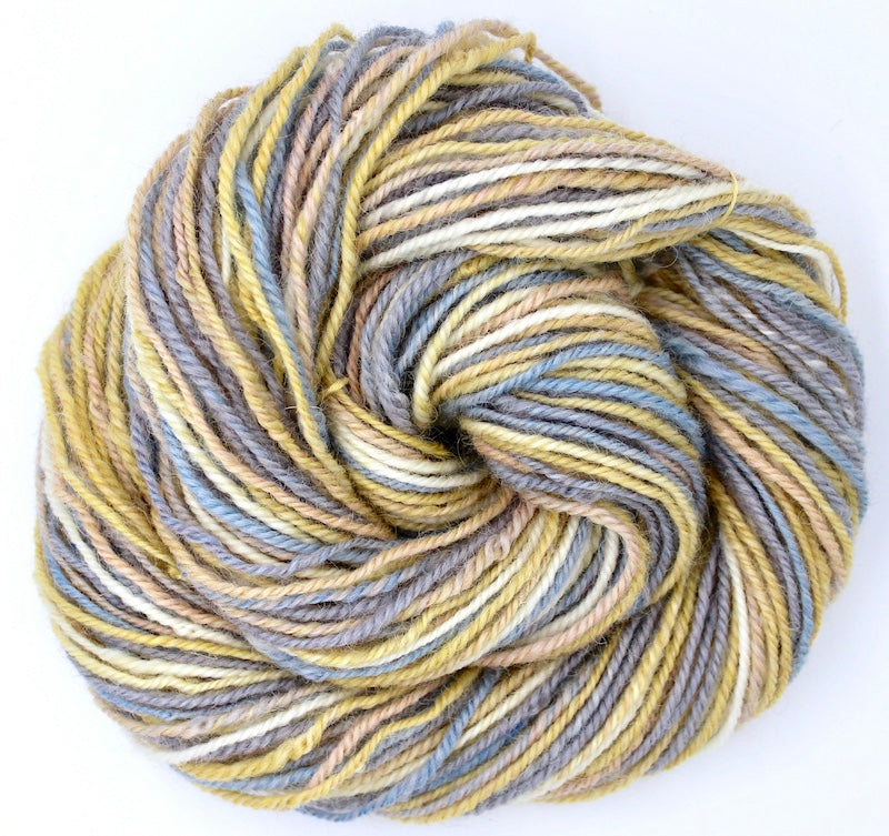 A one of a kind, hand dyed variegated skein of multicolored Grey, Baby Blue, Pastel Pink, Yellow, and White self-striping wool Yarn coiled attractively in the center of the frame. 
