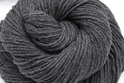 A close up shot of a skein of Vegan, Dark Heathered Charcoal Grey, 100% Cotton, Worsted weight Yarn recycled by hand from unwanted sweaters beautifully coiled in the center of the frame. 