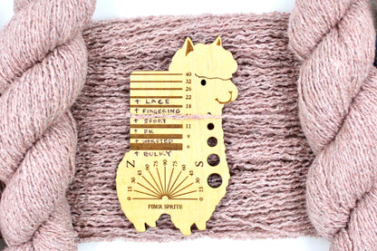 A skein of Vegan, Dusky Pink, Cotton, Polyester, Acrylic, Nylon, Sport Weight Yarn recycled by hand from unwanted sweaters draped over the center of the frame with one strand on top of a Llama shaped Yarn weight tool, to better illustrate the thickness of the yarn. 